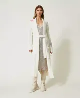 Vestido midi plateado de tirantes finos, cubierto completamente de lentejuelas. Presenta un escote en V ribeteado con encaje blanco y un sutil estampado floral en tonos pastel en la parte inferior.