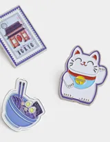 Set de tres pines metálicos esmaltados con diseño de elementos representativos de Tokyo: gato de la suerte, plato de ramen y estampilla con pagoda.