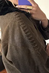 Campera bomber marrón de cuero ovino vintage, con cuello de piel sintética negra desmontable y cierre frontal con cremallera.
