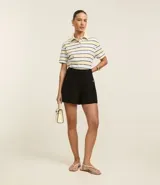 Short negro de tiro alto, corte sastrero, con bolsillos laterales con tachuelas metalizadas, bolsillos falsos traseros y cierre frontal.