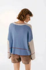 Sweater beige y azul con cuello en V y ribete bordeaux.