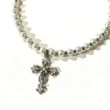 Collar corto de perlas blancas con dije de cruz plateada con incrustaciones de perlas pequeñas.
