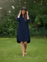 Vestido azul marino de algodón con cuello solapa y escote en V. Manga 3/4 regulable con presilla y botón. Bolsillos verticales laterales. Abertura central con botones en la espalda.