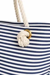 Bolso de tela tipo tote bag con estampado de rayas horizontales azules y blancas, y base de color beige. Tiene asas de cuerda de color beige.