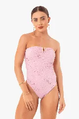 Traje de baño enterizo color rosa con textura arrugada, corte bandeau, herrajes dorados y copas extraíbles.