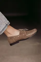Mocasín de cuero negro con cordones y tachas metálicas en la puntera.