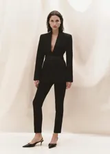 Pantalón negro de diseño crop, corte skinny y tiro medio. Cuenta con trabillas, dos bolsillos laterales, dos bolsillos de ribete en la parte posterior, cierre de cremallera y botón, y forro interior.