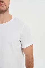 Remera blanca de algodón con cuello redondo y estampado de tablas de surf y un sol.