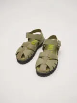 Sandalias romanas color verde oliva, con tiras entrecruzadas y hebilla lateral. Suela de goma negra con plataforma de 3cm. Fabricadas en cuero vacuno.