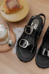 Sandalias rojas de cuero charol con hebillas plateadas y suela track.