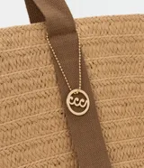 Bolso de playa tipo tote de paja color beige con asas de tela marrón.