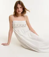 Vestido midi blanco con tirantes finos y escote cuadrado. Presenta bordados de caracolas en el busto y lazo en la espalda.
