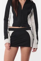 Minifalda deportiva gris con recortes laterales en negro y logo estampado en la parte trasera. Cierre invisible en el lateral.