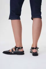 Ballerinas negras de cuero con punta fina, tres tiras sobre el empeine con hebillas plateadas y talón descubierto.