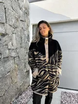 Buzo de polar con cuello alto, cierre de botones a presión y estampado de cebra en tonos beige y negro.