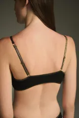 Top de bikini negro con ribete dorado y aro metálico en el centro del busto.