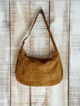 Bolso de hombro color blanco con textura craquelada, correa regulable con hebilla, interior forrado y cierre superior. Incluye llavero y bolsillos internos.