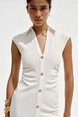 Vestido midi color gris topo, de cuello camisero y escote pico con manga corta. Tiene detalle de drapeado lateral y cierre frontal con botones metálicos.
