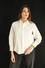 Camisa blanca de corte clásico con bolsillo en el pecho, mangas largas y botones al tono.