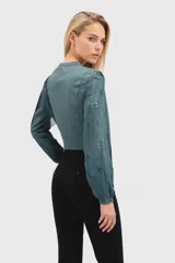 Camisa verde azulado con escote en V, mangas largas abullonadas y cierre frontal con botones.