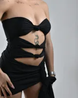 Minivestido negro ajustado al cuerpo, con escote strapless, múltiples aberturas en el torso y falda drapeada con lazo lateral.