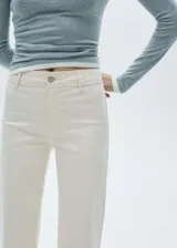 Pantalón de jean culotte color crema, tiro alto, con cierre de cremallera y botón, trabillas, bolsillos traseros, bajo deshilachado y tejido elástico.