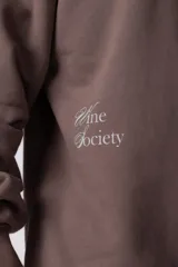 Buzo color beige de frisa con cuello redondo, mangas largas y logo bordado en el pecho.