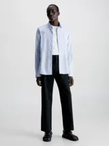 Camisa celeste de popelín de algodón elástico, corte slim, con cierre frontal de botones, mangas largas y monograma de Calvin Klein bordado en el pecho.