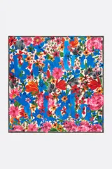 Pañuelo cuadrado de poliéster reciclado con estampado de flores multicolores y logo en acuarela sobre fondo azul.