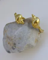 Brazalete rígido dorado con forma de caracola en los extremos.