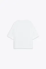 Blusa marrón de lino 100% con cuello redondo, manga corta, bolsillo de parche en el pecho y bajo asimétrico con aberturas laterales.