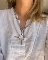 Collar plateado con cadena gruesa y dije grande con forma de sol.