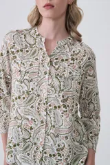 Camisa de manga larga con cuello mao y estampado paisley en tonos blanco, verde oliva y rosado. Presenta un calce holgado y bolsillos frontales.