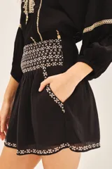 Minifalda blanca de algodón con bordados geométricos negros en el ruedo y cintura.