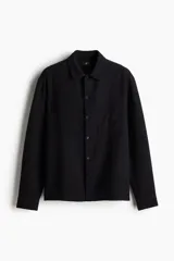 Camisa negra de algodón texturizado, corte regular fit, con cuello inglés, tapeta clásica, bolsillo superior y canesú en la espalda. Mangas largas con puños abotonados y bajo recto.