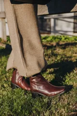 Bota corta color crema con textura de reptil, caña media, punta cuadrada, cierre lateral y taco de madera.