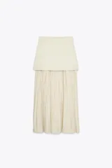 Falda midi color crema, de tiro alto con cintura elástica y tejido plisado semitransparente.