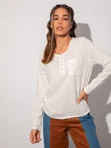 Remera de manga larga color blanco con detalle de bolsillo frontal y cuello con botones metálicos.
