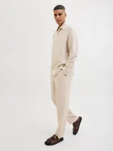 Pantalón chino de lino color beige, corte clásico, con cierre de cremallera y cintura con elástico.