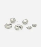 Set de tres pares de aros plateados: un par de argollas con strass, un par de argollas gruesas y un par de aros tipo piercing.
