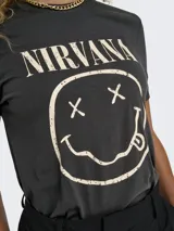 Remera negra de algodón con cuello redondo y mangas cortas. Estampado frontal con el logo de la banda Nirvana y el dibujo de la cara sonriente.