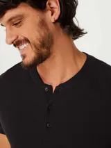 Camiseta color beige con cuello redondo abotonado y mangas cortas.