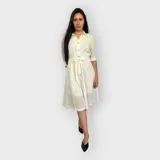 Vestido camisero midi negro con cuello clásico, mangas 3/4 y falda acampanada. Presenta un cinturón de lazo en la cintura y cierre frontal con botones.