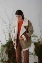 Gamulán de paño color beige, con detalles en cuero y forro de peluche, de corte holgado y manga larga.