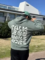 Canguro verde oliva con capucha y estampado en la espalda con la frase "Talk Less Smile More".