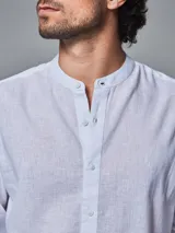 Camisa blanca de lino con cuello mao y mangas largas con presilla para enrollar.