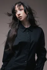 Vestido corto negro estilo camisero con botones frontales, mangas largas y lazos laterales ajustables.