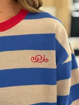 Remerón oversize de algodón a rayas horizontales azules y beige, con cuello redondo y ribete rojo.