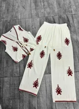 Conjunto de pantalón y chaleco blancos con bordados rojos. El chaleco es corto, con escote en V y se ata en el frente. El pantalón es recto y de tiro alto.