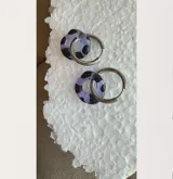 Aros colgantes con aro de acero y dije circular de cristal de Murano color lila con manchas negras.